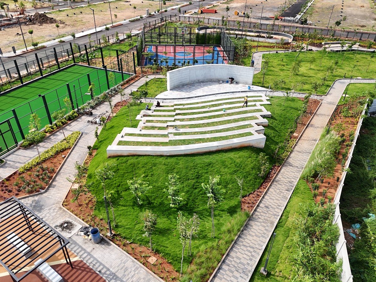 Tiered grass amphitheatre beside sports courts and gardens