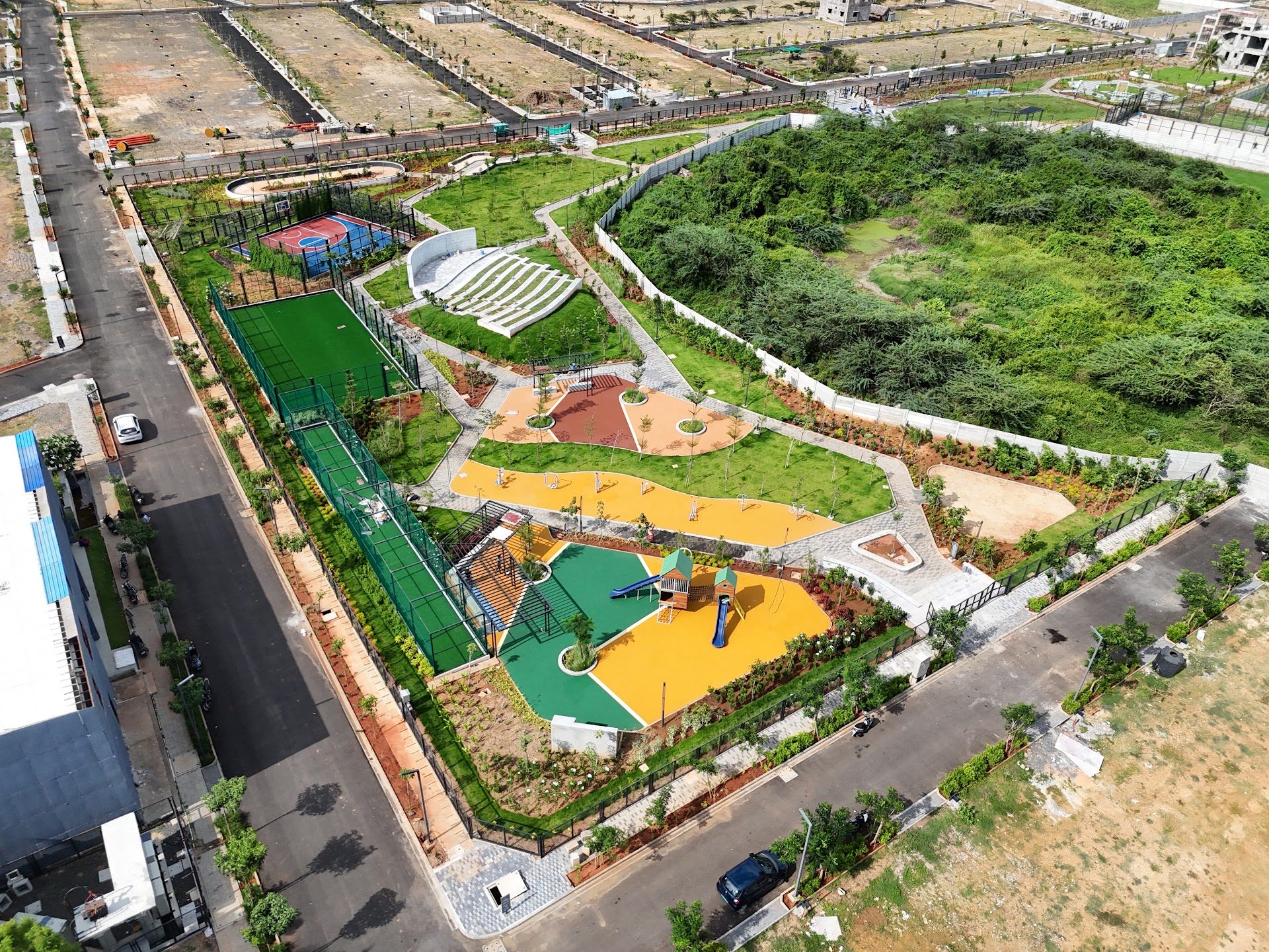 Aerial view of a completed amenity landscape with play areas, lawns, sports courts and pathways