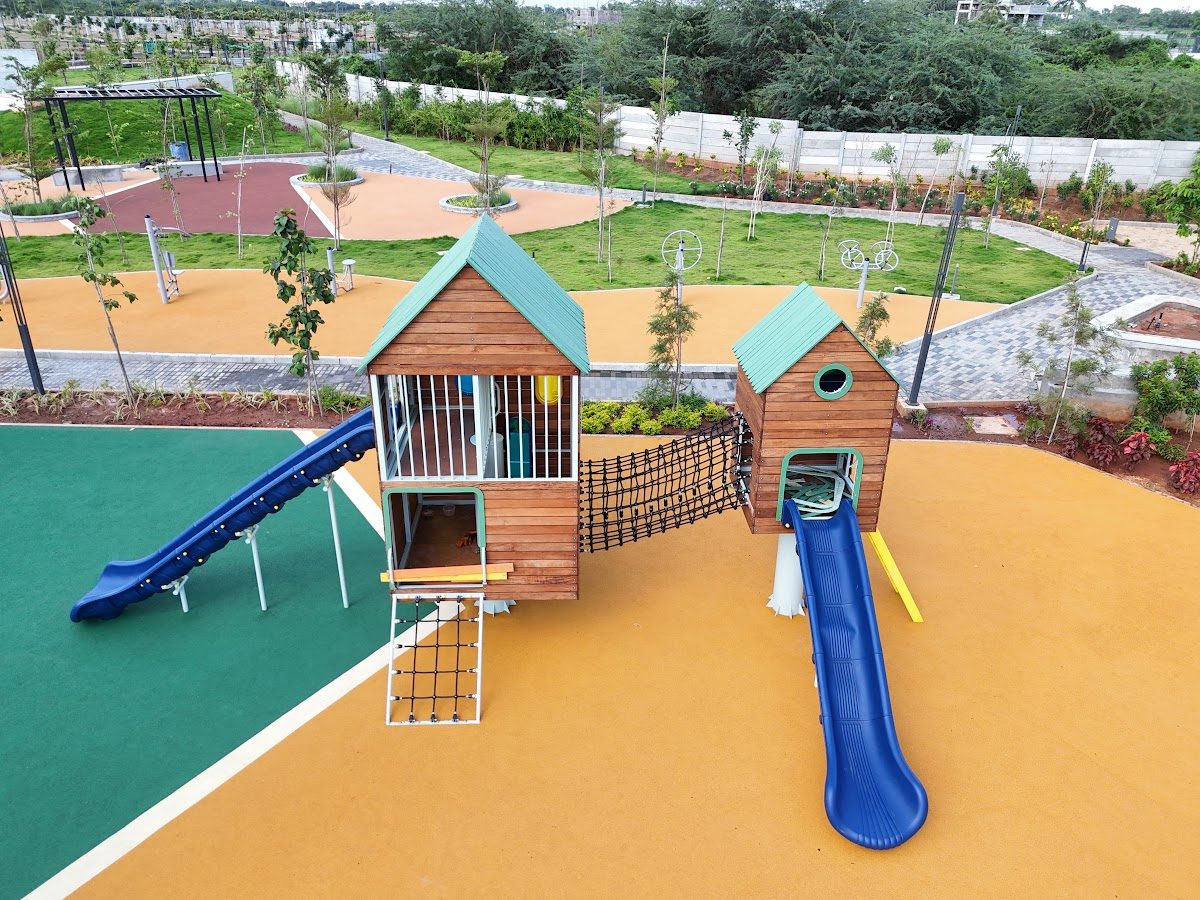 Wooden play houses with blue slides on orange safety flooring